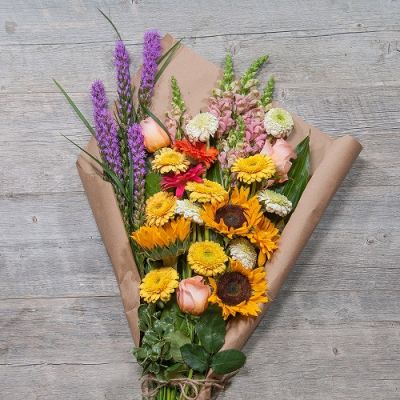 Colorful bouquet of flowers wrapped in brown paper