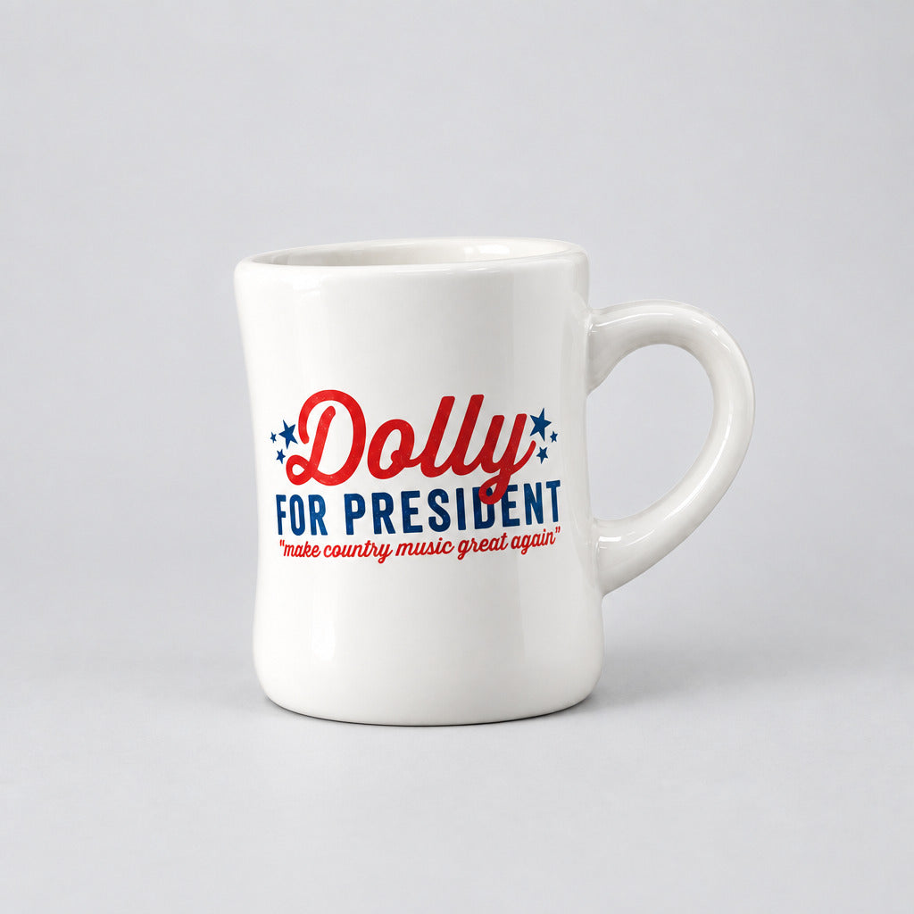 A white ceramic mug with the text 'Dolly FOR PRESIDENT' in red and blue, subheading: make country music great again