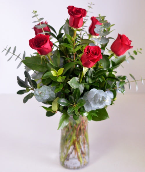 Six Red Roses with pretty foliage arranged in a clear glass vase by Scent & Violet floral designers in Houston, TX