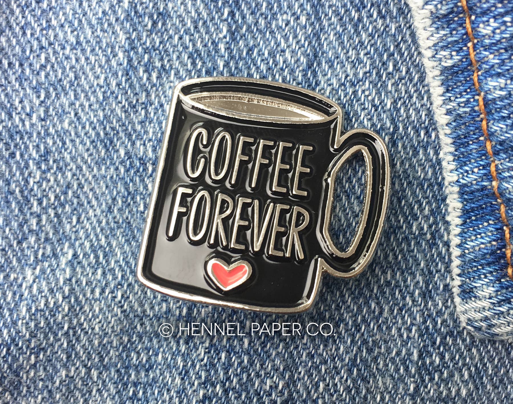 Enamel pin of a coffee mug with 'Coffee Forever' text on denim fabric by hennel paper co