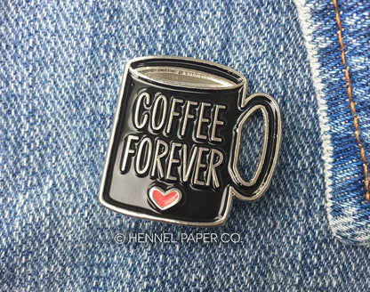 Enamel pin of a coffee mug with 'Coffee Forever' text on denim fabric by hennel paper co
