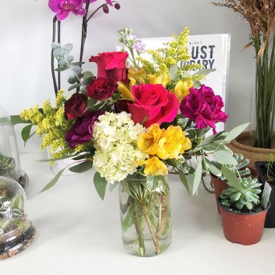Colorful flower arrangement in a clear mason jar vase 